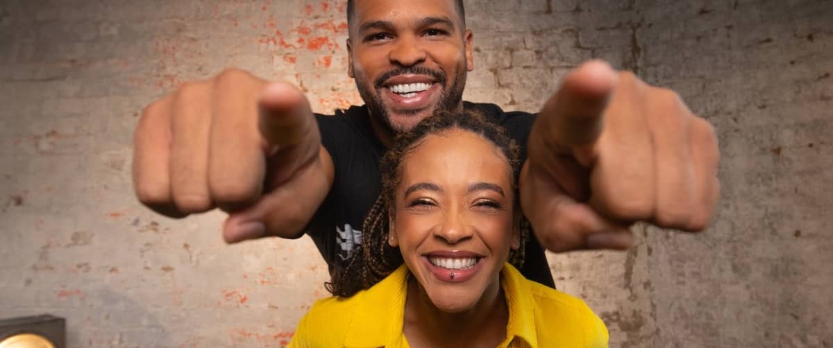 Joe Lycett wearing a stand up to cancer top, in a shouting pose.